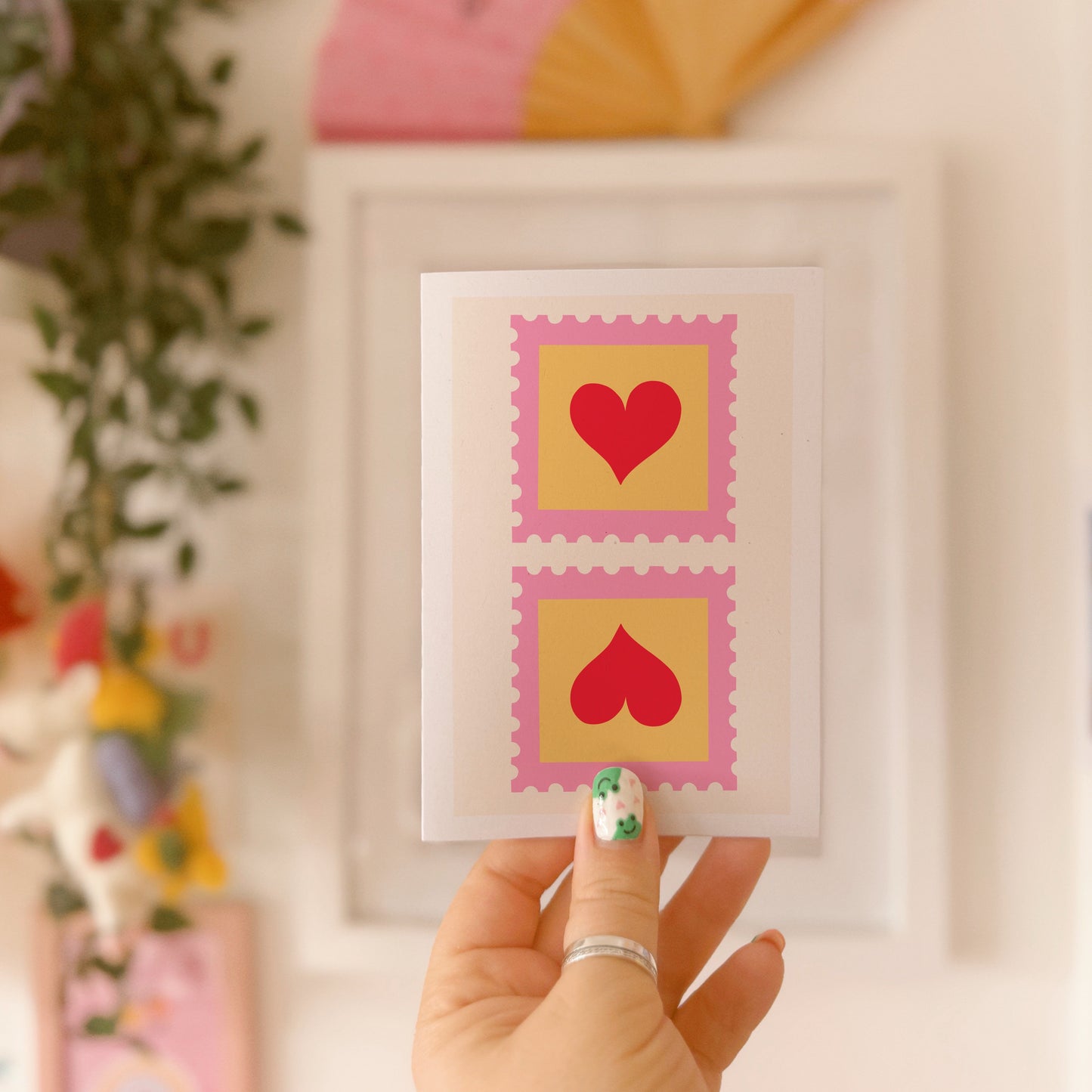 A greetings card with two illustrated postage stamps with red love hearts on.