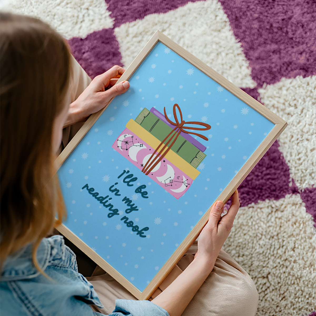 A cute pink print, featuring an illustration of a pack of books, and the quote 'I'll be in my reading nook' underneath.