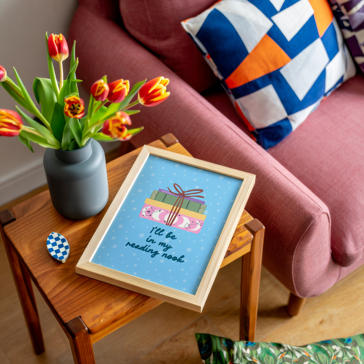 A cute pink print, featuring an illustration of a pack of books, and the quote 'I'll be in my reading nook' underneath.