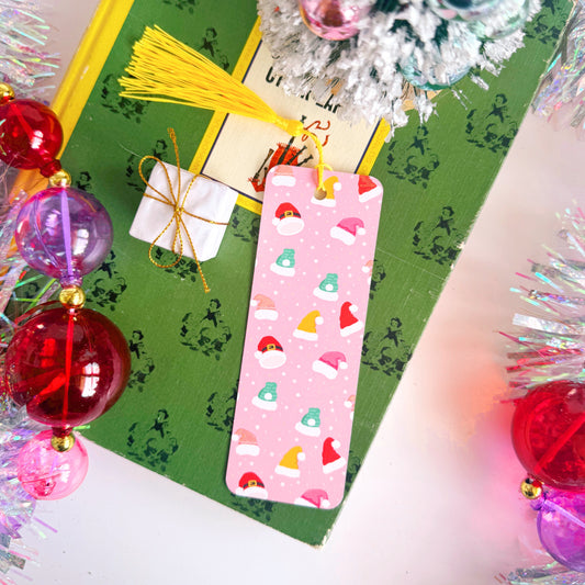An image showing the front side of a Christmas bookmark - that has multicoloured Santa and Elf hats on the front.