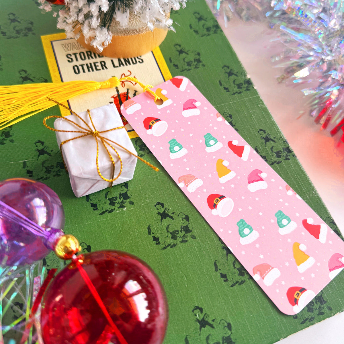 An image showing the front side of a Christmas bookmark - that has multicoloured Santa and Elf hats on the front.
