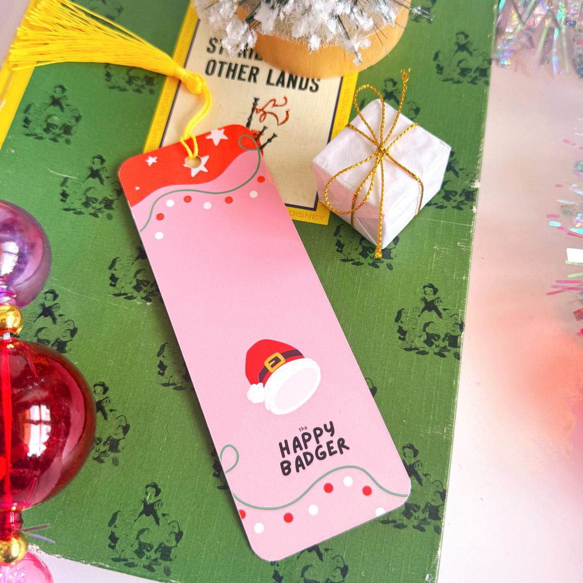 An image showing the reverse side of a Christmas bookmark - that has a festive pattern with the Happy Badger branding logo.