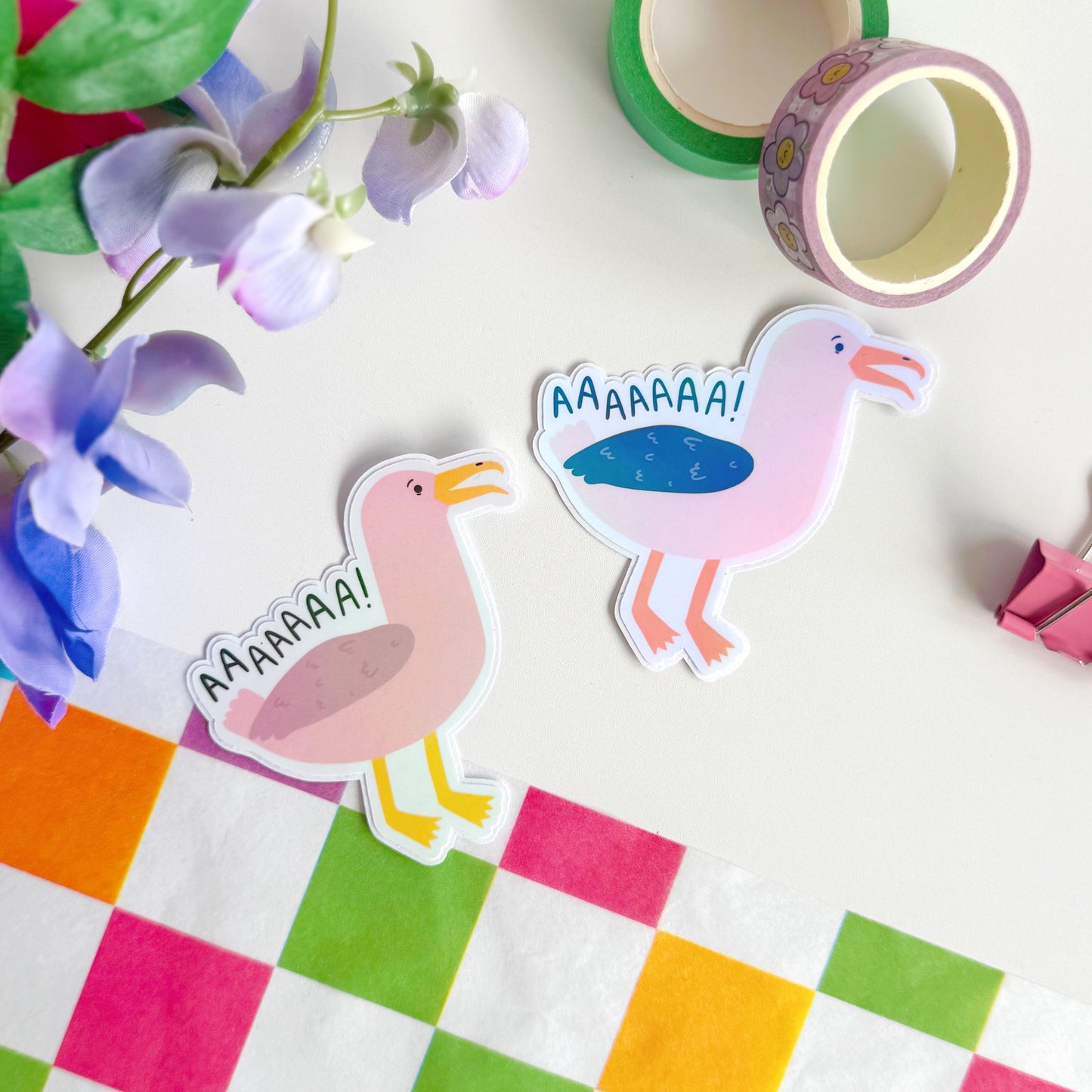 An image showing two holographic stickers of seagulls, one in pink one in more life-like colours. The text reads 'AAAAAAA!' as if the seagulls are screaming.
