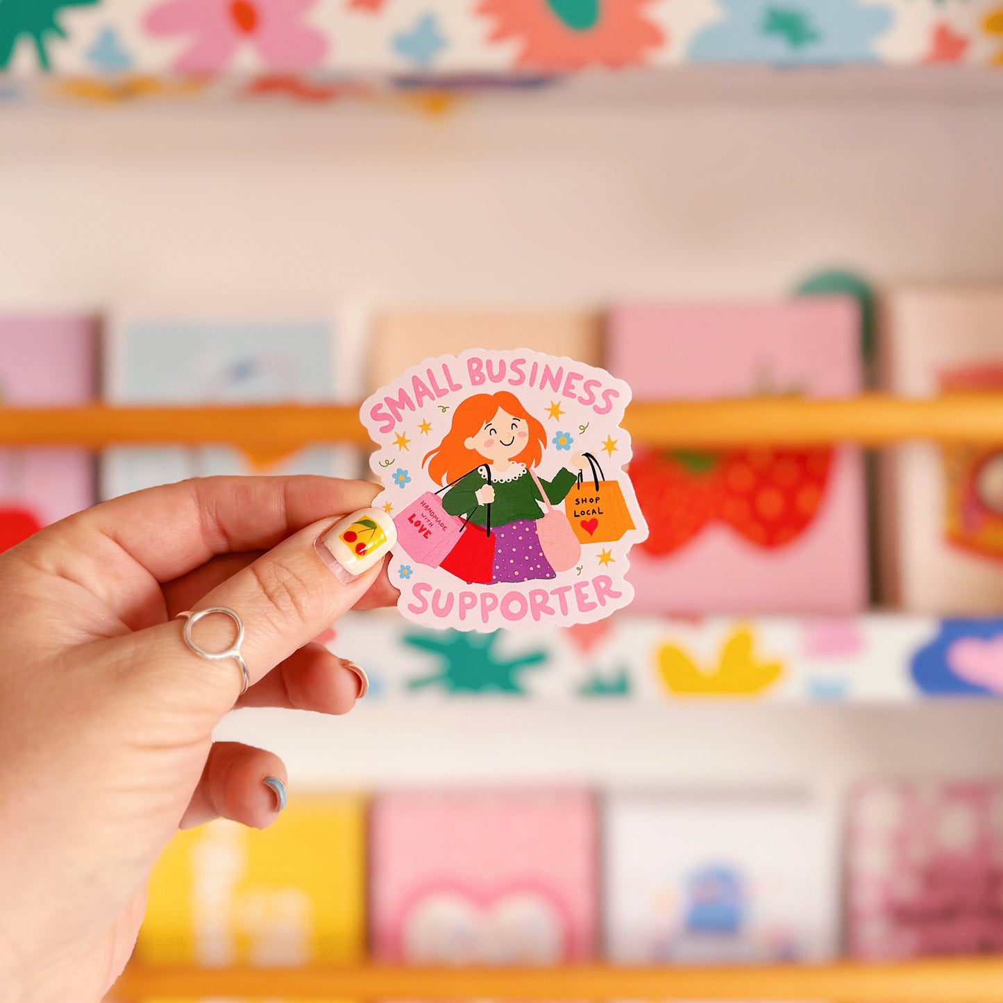 A vinyl sticker with n illustration of a girl holding shopping bags and text that reads 'Small Business Supporter'.