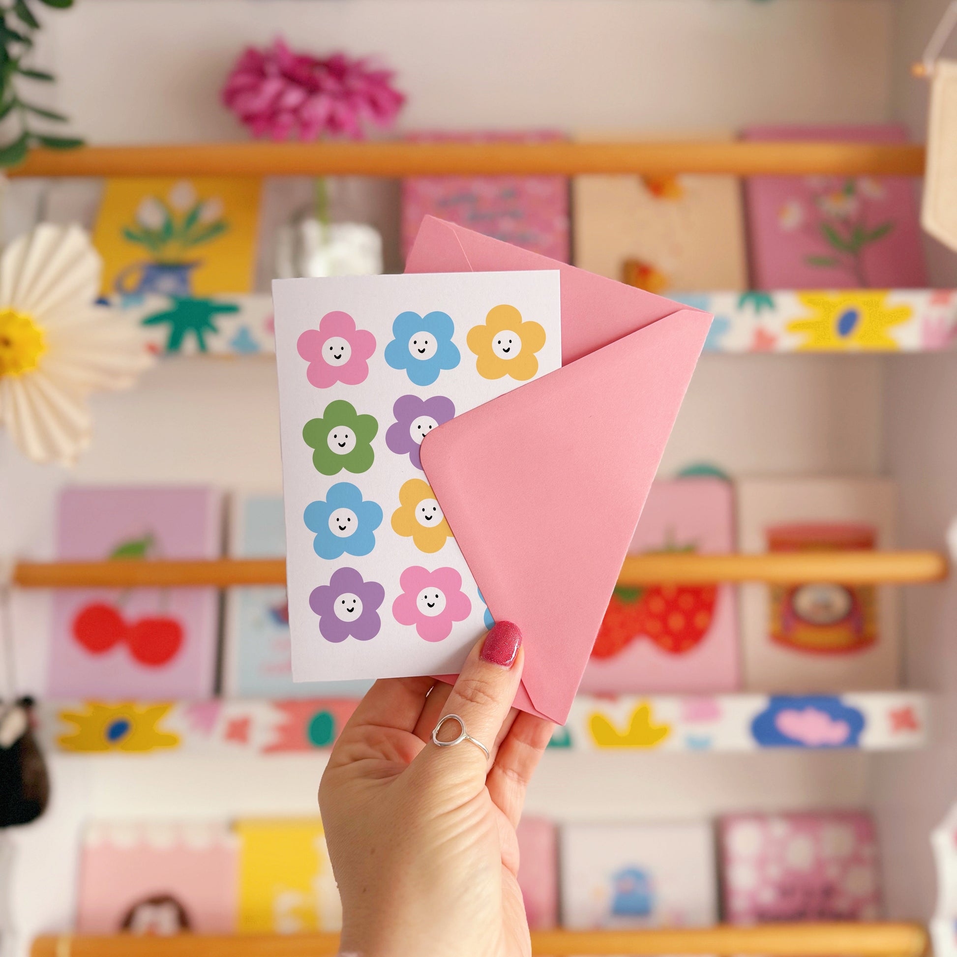 A greetings card with 12 different coloured smiling daisies on the front.