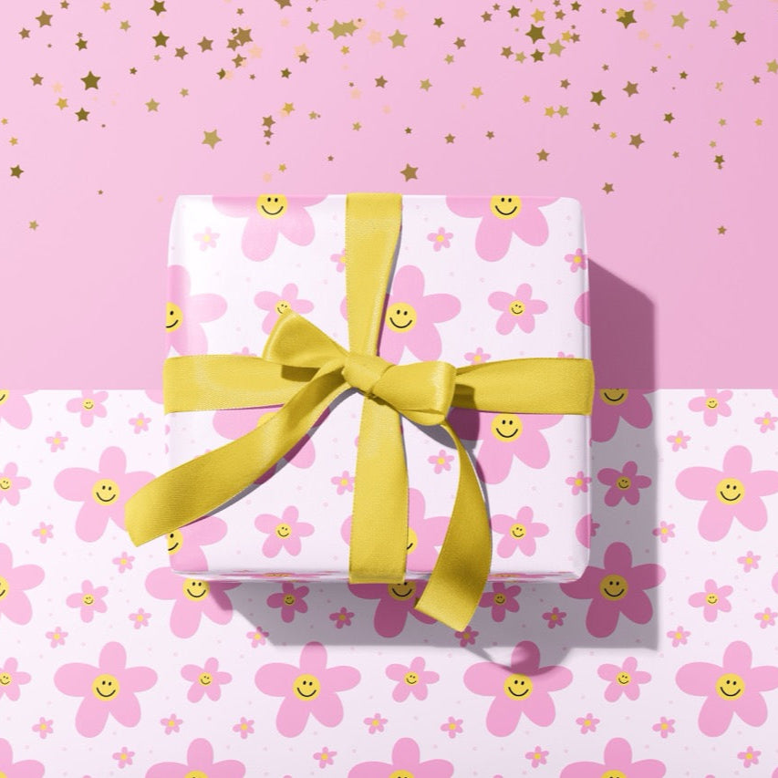 A gift wrapped present, wrapped up in cute smiling flower print gift wrap from The Happy Badger.