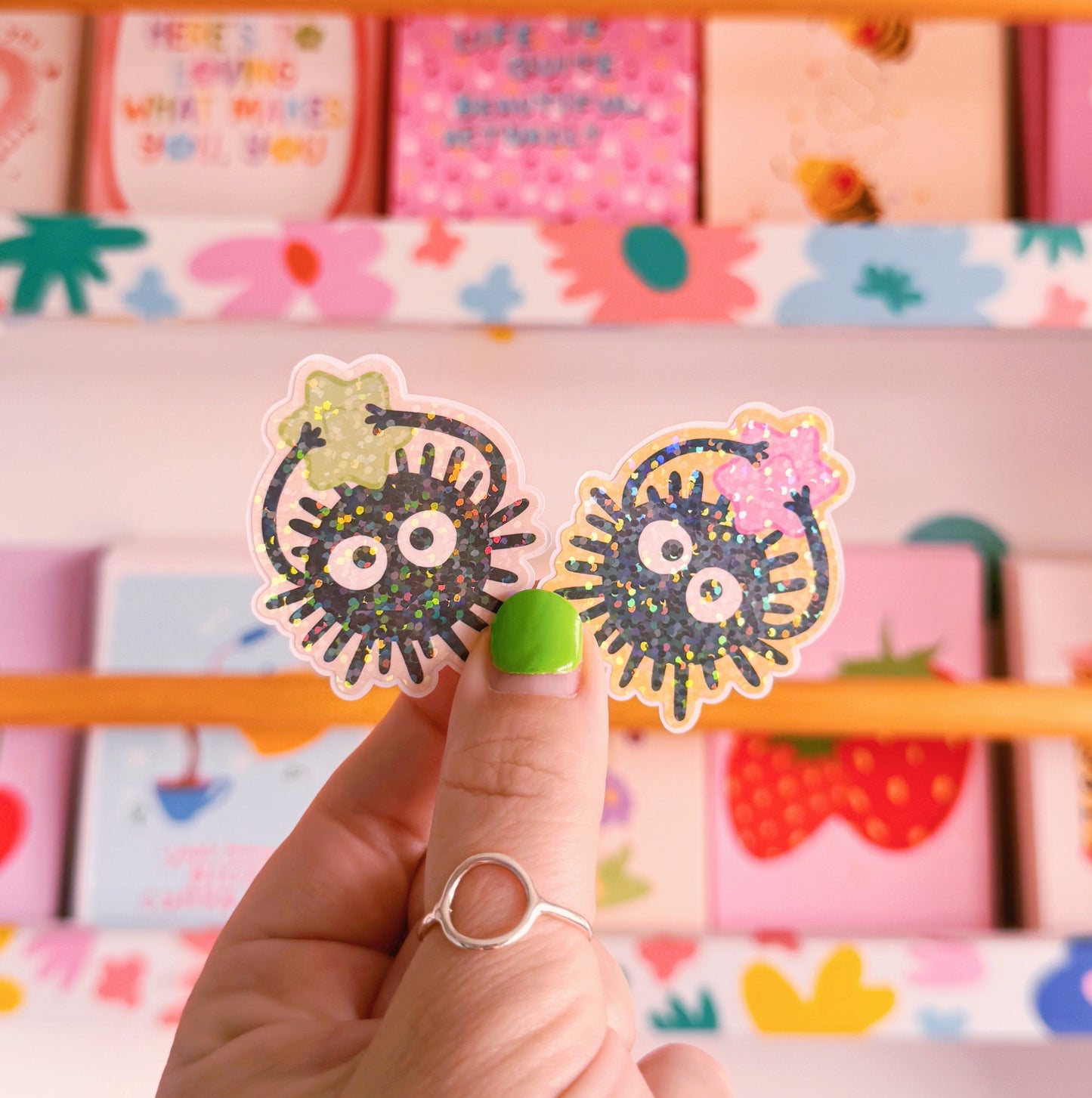 Two small die-cut stickers featuring illustrations of Ghibli-inspired Soot Sprites, one with a green star and one with a pink star.