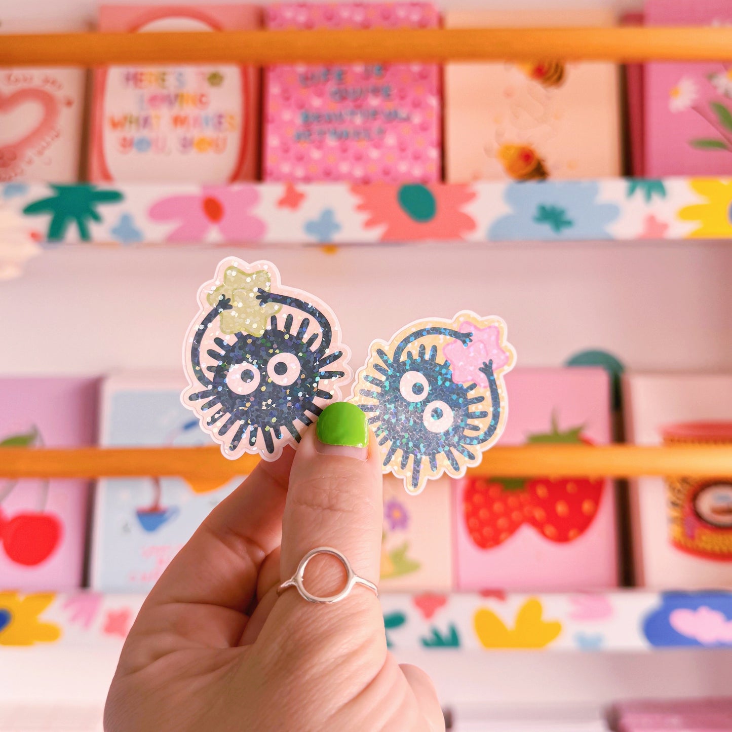 Two small die-cut stickers featuring illustrations of Ghibli-inspired Soot Sprites, one with a green star and one with a pink star.