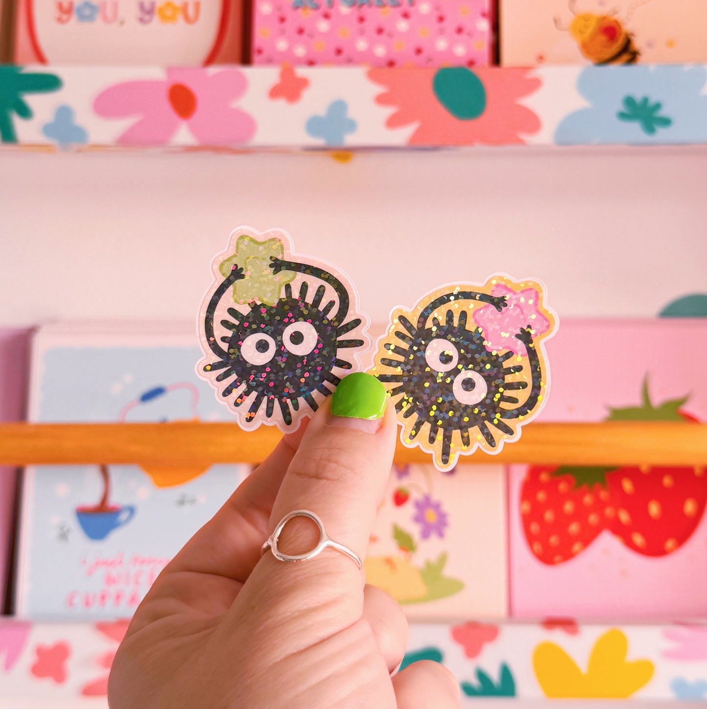 Two small die-cut stickers featuring illustrations of Ghibli-inspired Soot Sprites, one with a green star and one with a pink star.