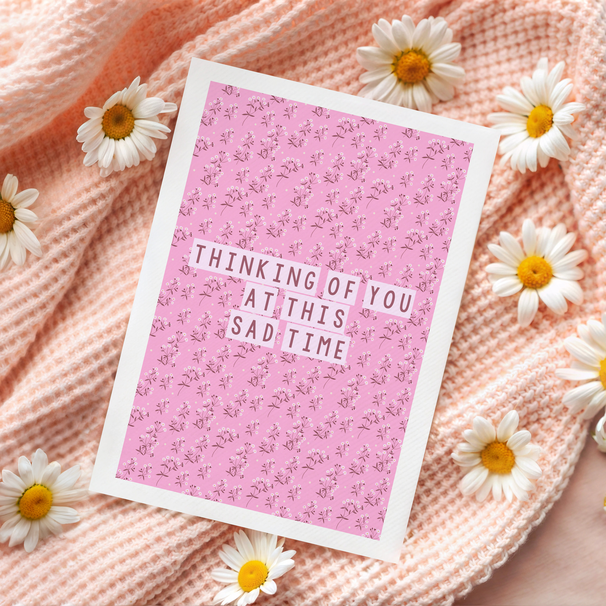 A card with a pink floral patterned background, and the words 'thinking of you at this sad time' in the centre.