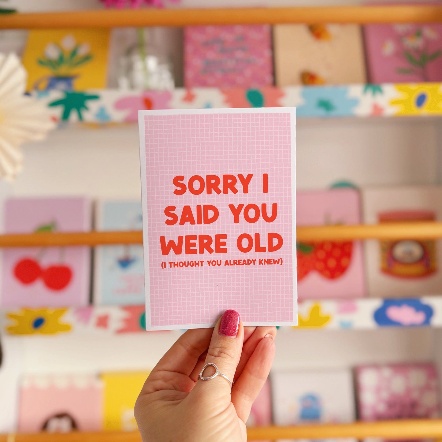 A pink and red birthday card, with a humorous saying on the front - "Sorry I Said You Were Old (I thought you already knew)"