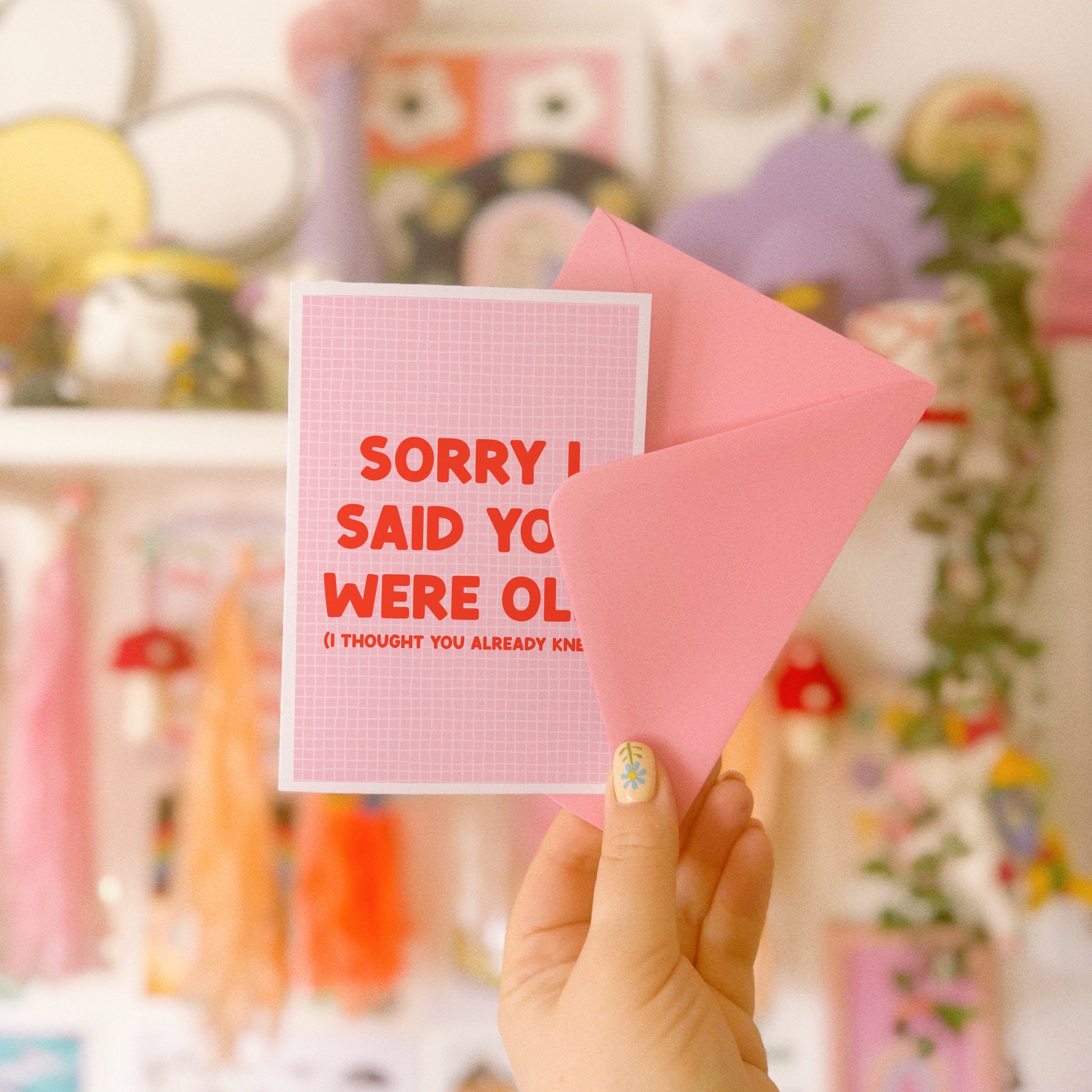 A pink and red birthday card, with a humorous saying on the front - "Sorry I Said You Were Old (I thought you already knew)"