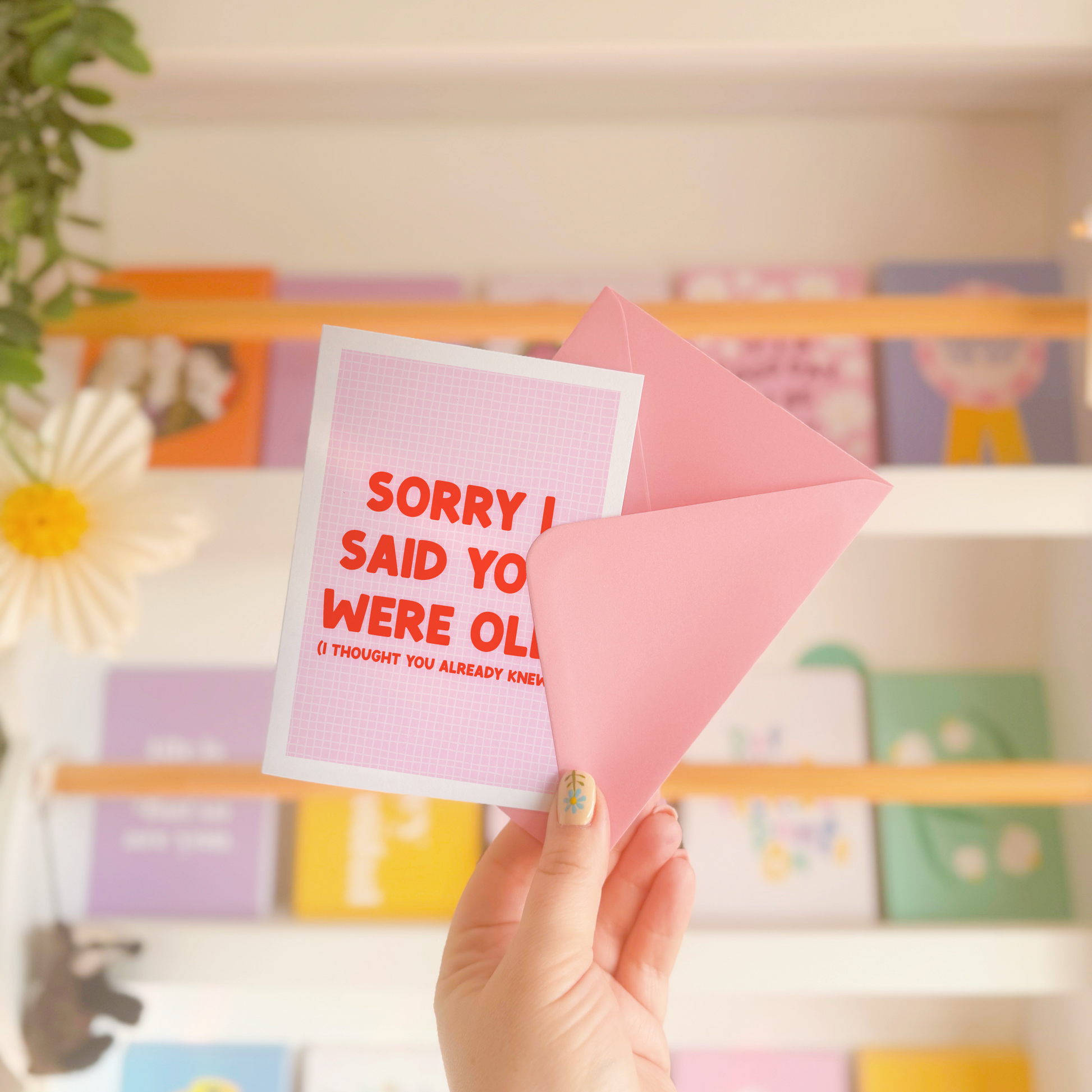 A pink and red birthday card, with a humorous saying on the front - "Sorry I Said You Were Old (I thought you already knew)"