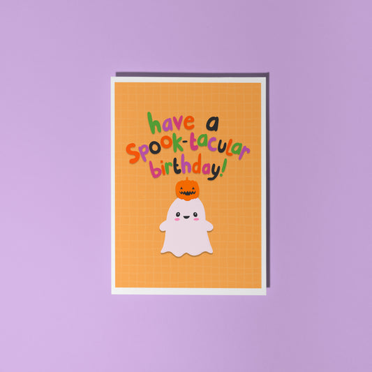 A halloween themed birthday card, with a cute ghost illustration and writing that says 'have a spook-macular birthday!'.