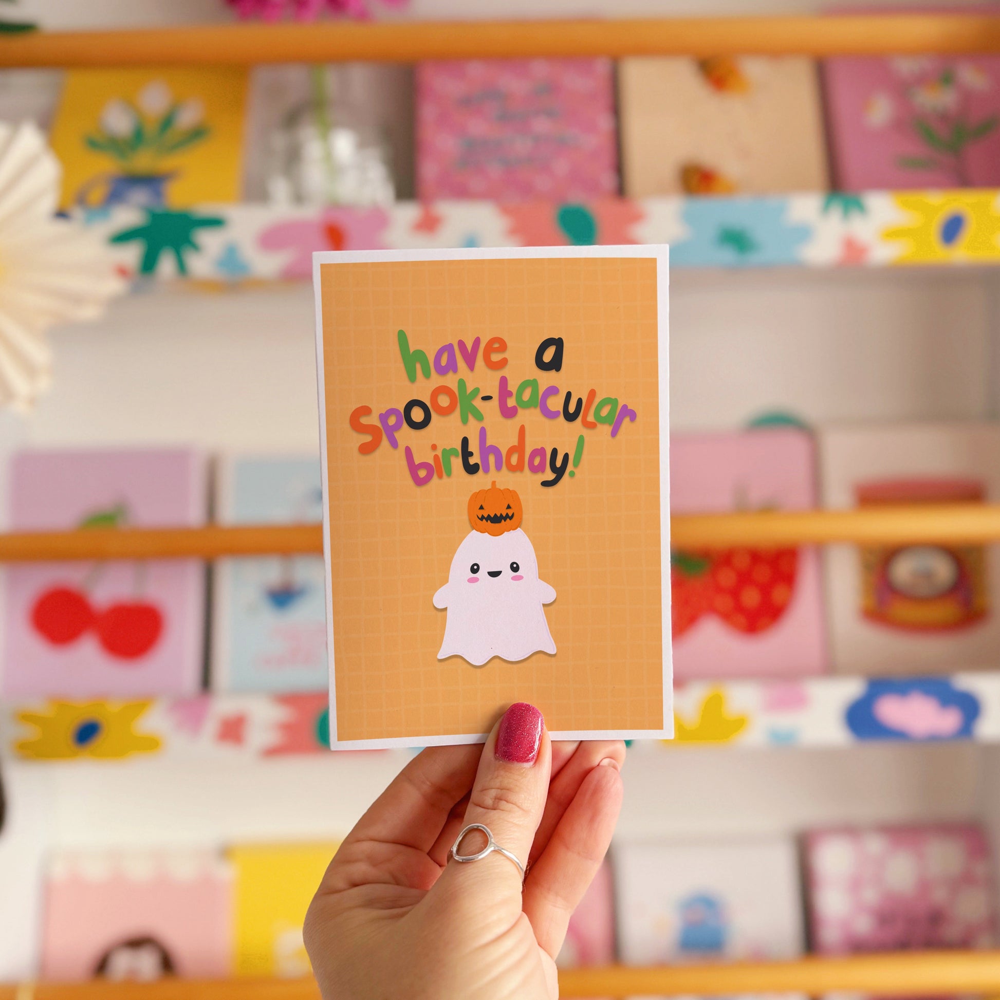 A halloween themed birthday card, with a cute ghost illustration and writing that says 'have a spook-macular birthday!'.