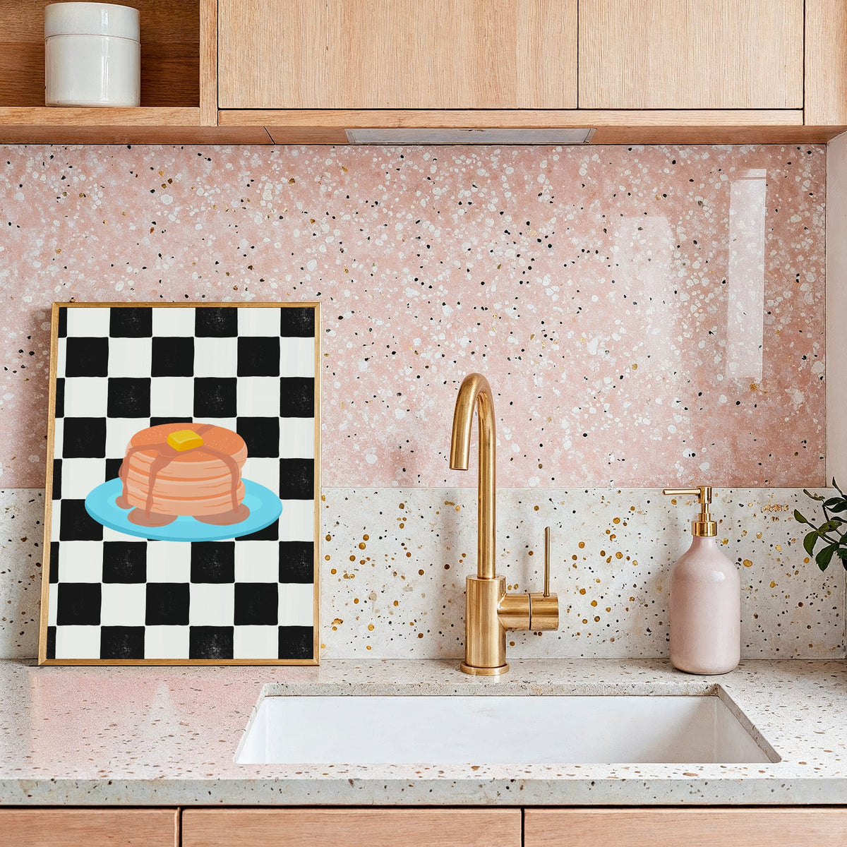 A framed art print featuring a black and white checkered pattern with a colourful illustration of pancakes on a blue plate.