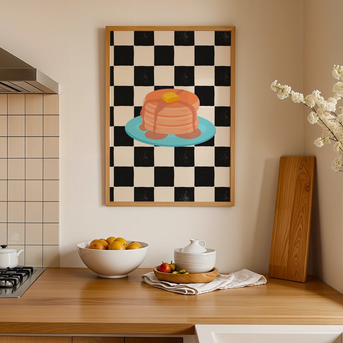 A framed art print featuring a black and white checkered pattern with a colourful illustration of pancakes on a blue plate.