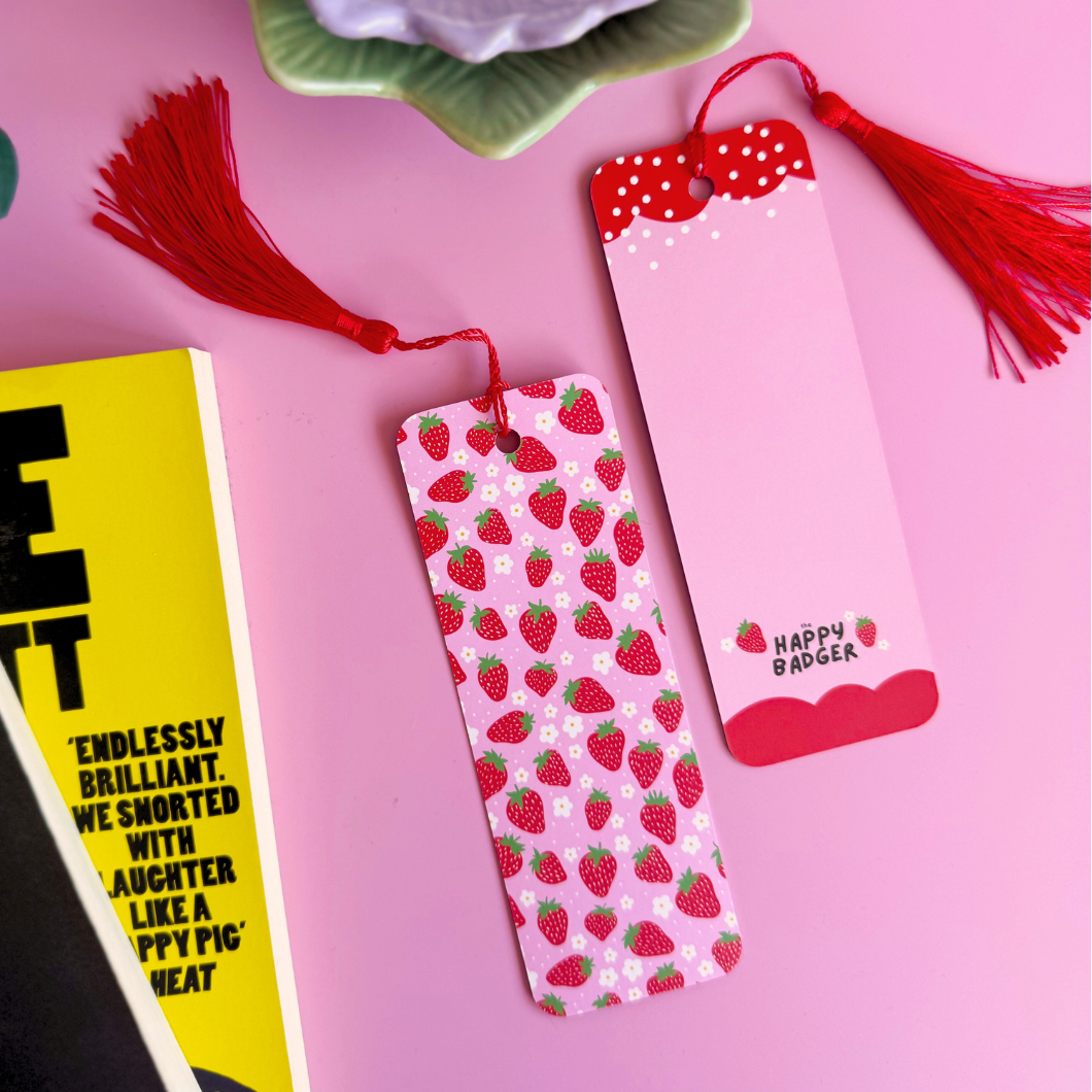 A pink and red strawberry patterned bookmark with a coordinating red tassel.