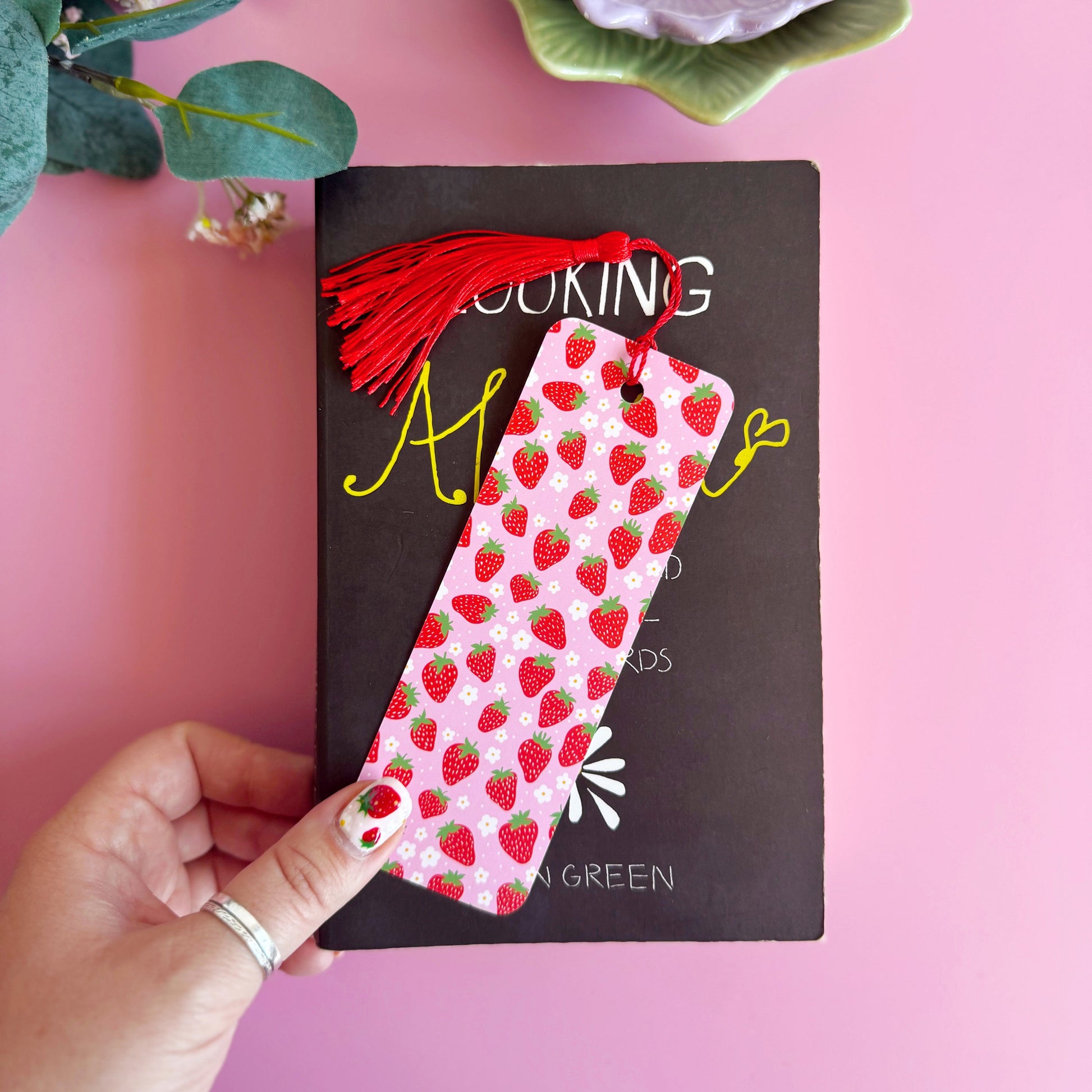 A pink and red strawberry patterned bookmark with a coordinating red tassel.
