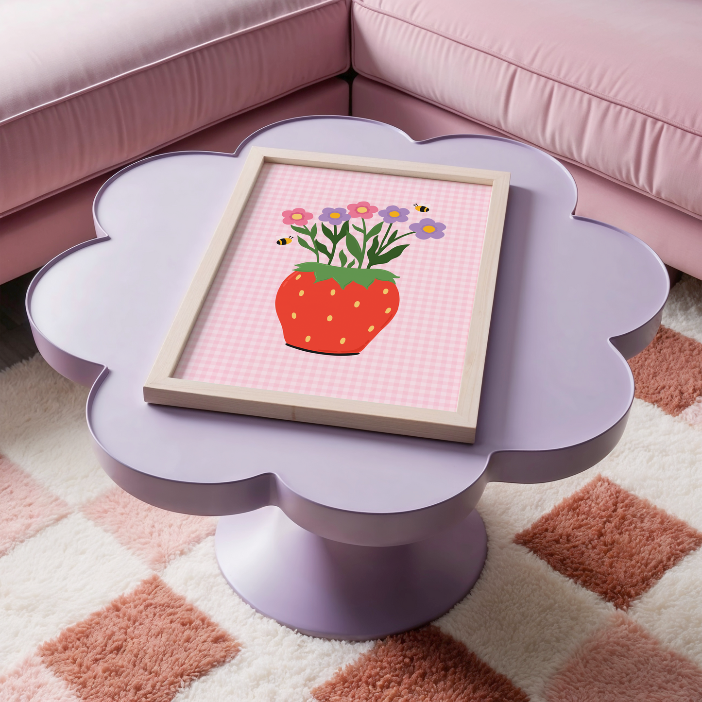 Framed artwork of a strawberry with flowers on a pink table in a room with pink furniture.