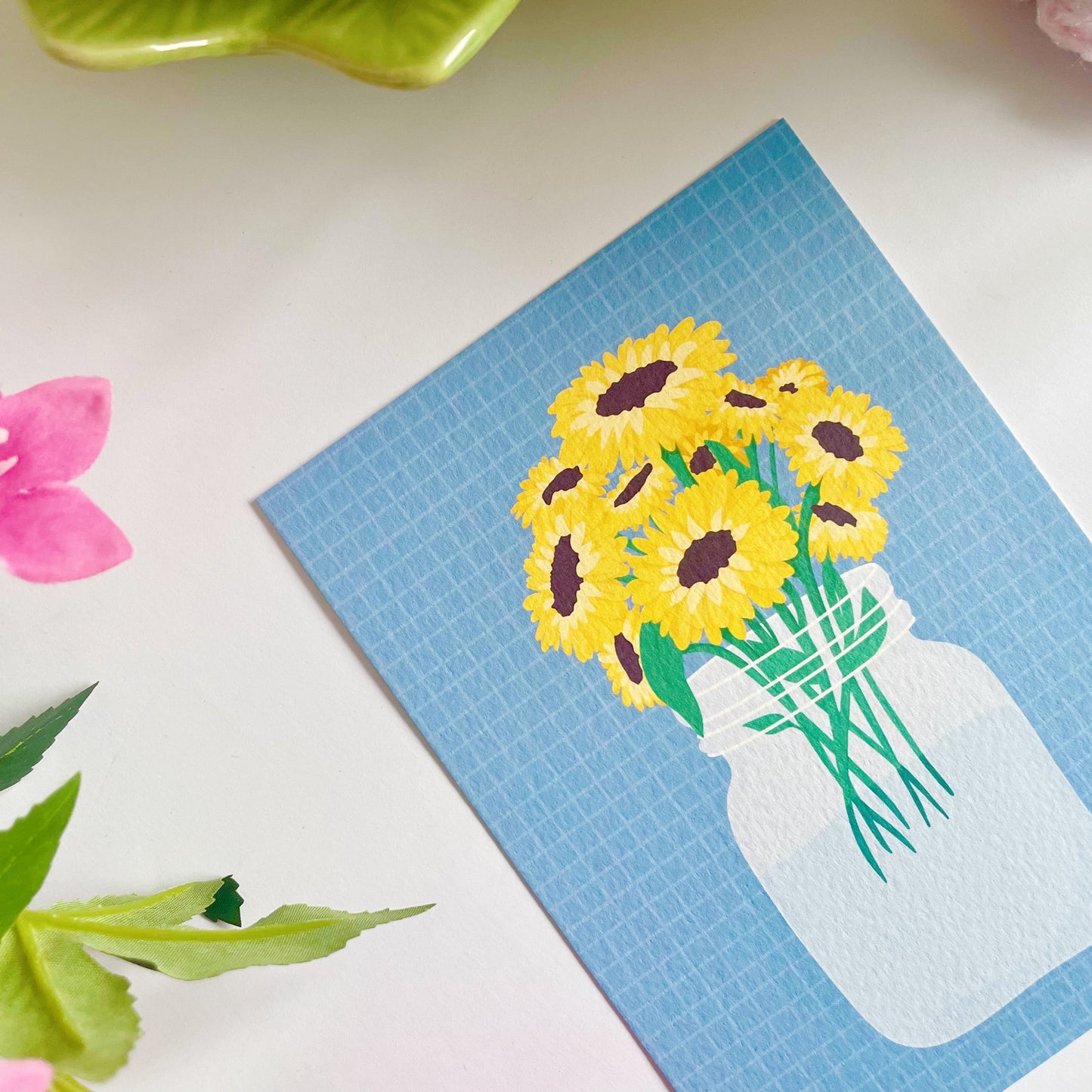 A textured postcard, with an illustration of a vase of sunflowers on the front.