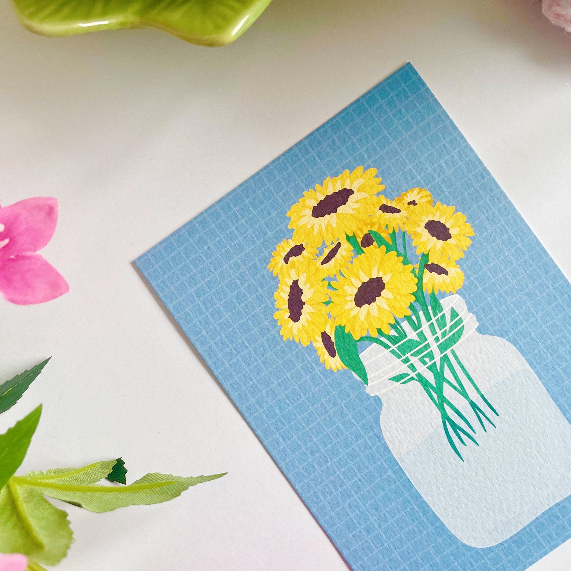 A textured postcard, with an illustration of a vase of sunflowers on the front.