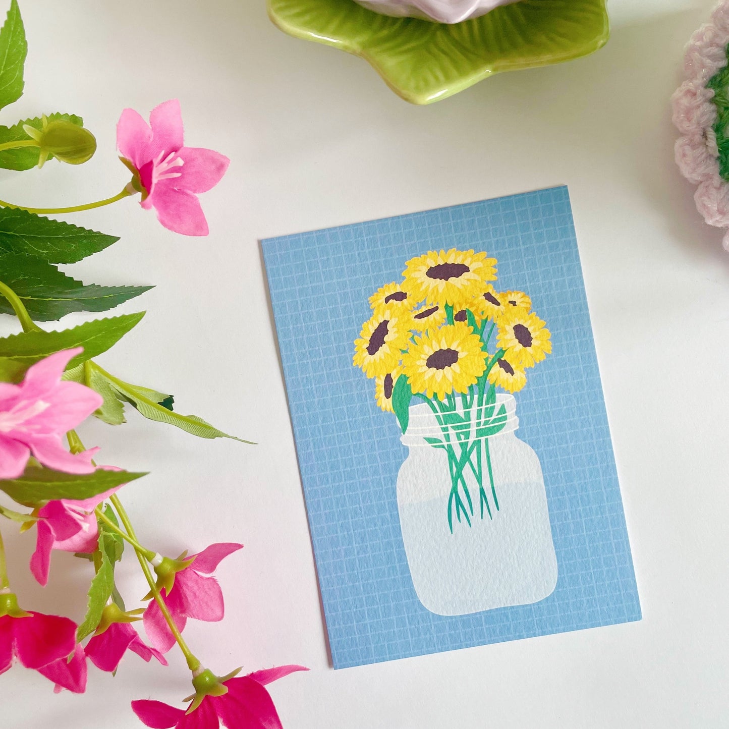 A textured postcard, with an illustration of a vase of sunflowers on the front.