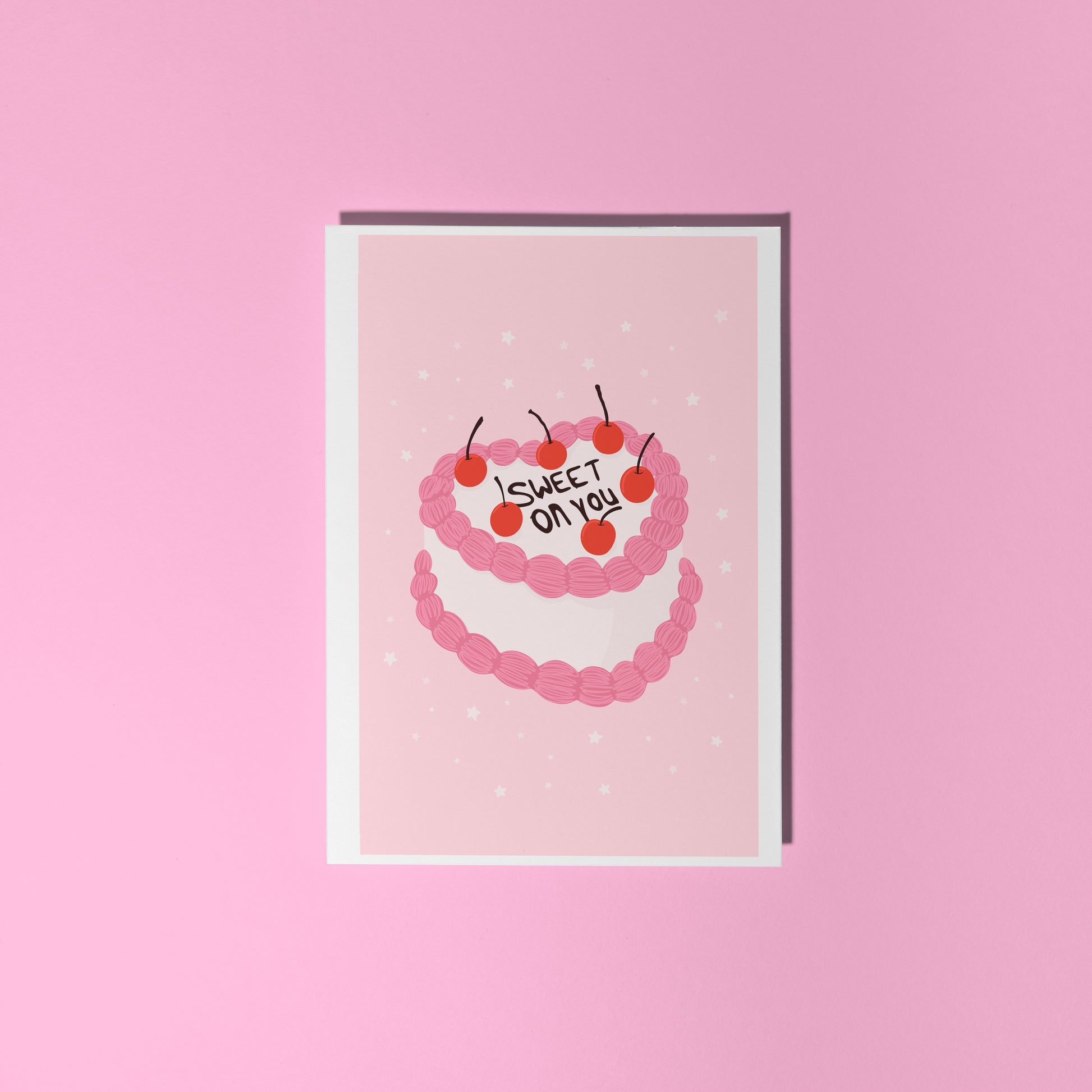 A pink greetings card with an illustration of a cake with pink and white icing, that says 'sweet on you' on the top of the cake.