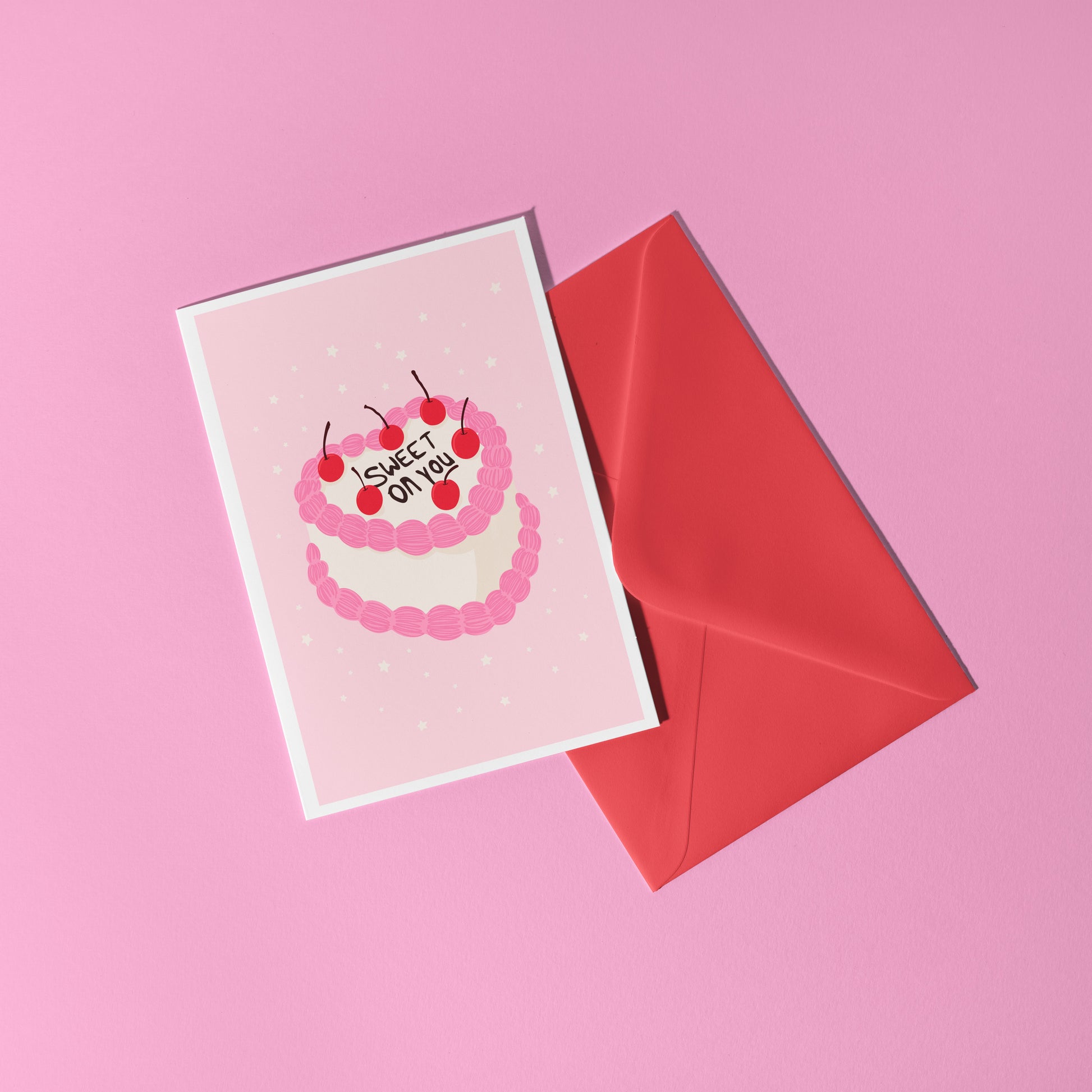 A pink love themed card, with a cake illustration. There is black icing on the cake says 'sweet on you' and the rest of the cake has cherries and pink and white icing.
