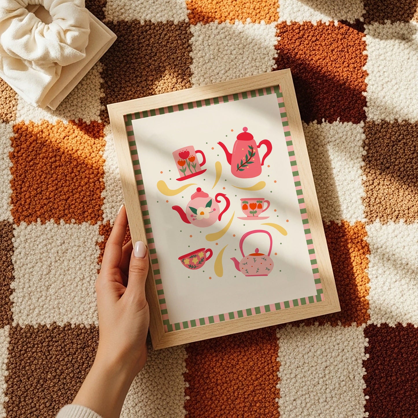 An illustration of 6 mugs and teapots in cosy autumnal colours. The print has a pink and green checkerboard border.