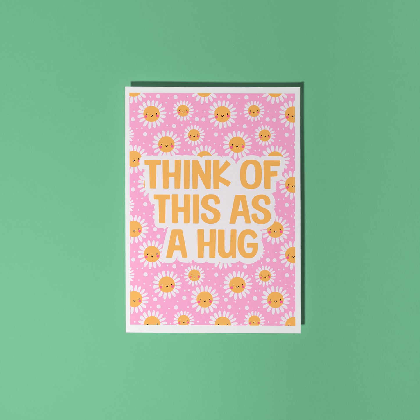 Hand holding a pink card with yellow smiling flowers and text that says 'Think of this as a hug'.