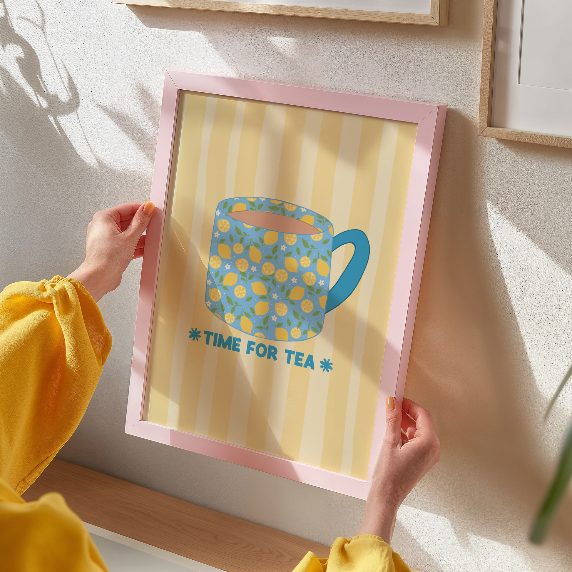 Framed artwork with a blue mug and 'Time for Tea' text on a yellow striped background.