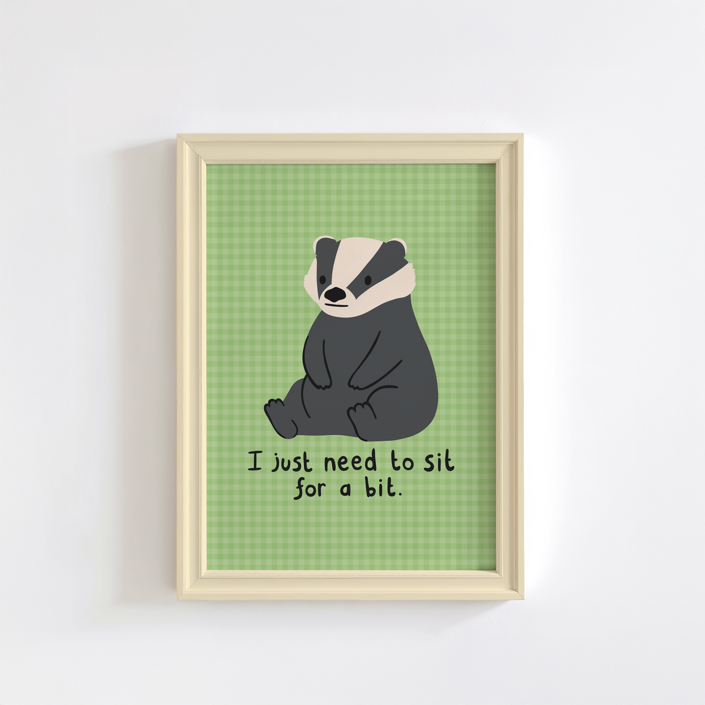A green gingham print, with an illustration of a badger sat down, and a quote that reads 'I just need to sit for a bit'.