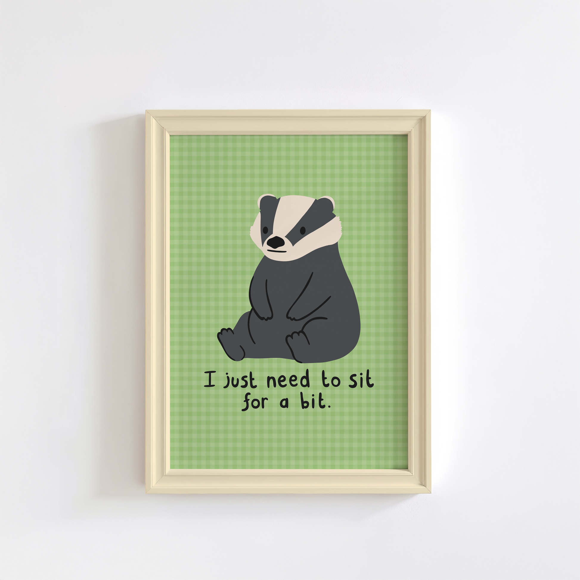 A green gingham print, with an illustration of a badger sat down, and a quote that reads 'I just need to sit for a bit'.