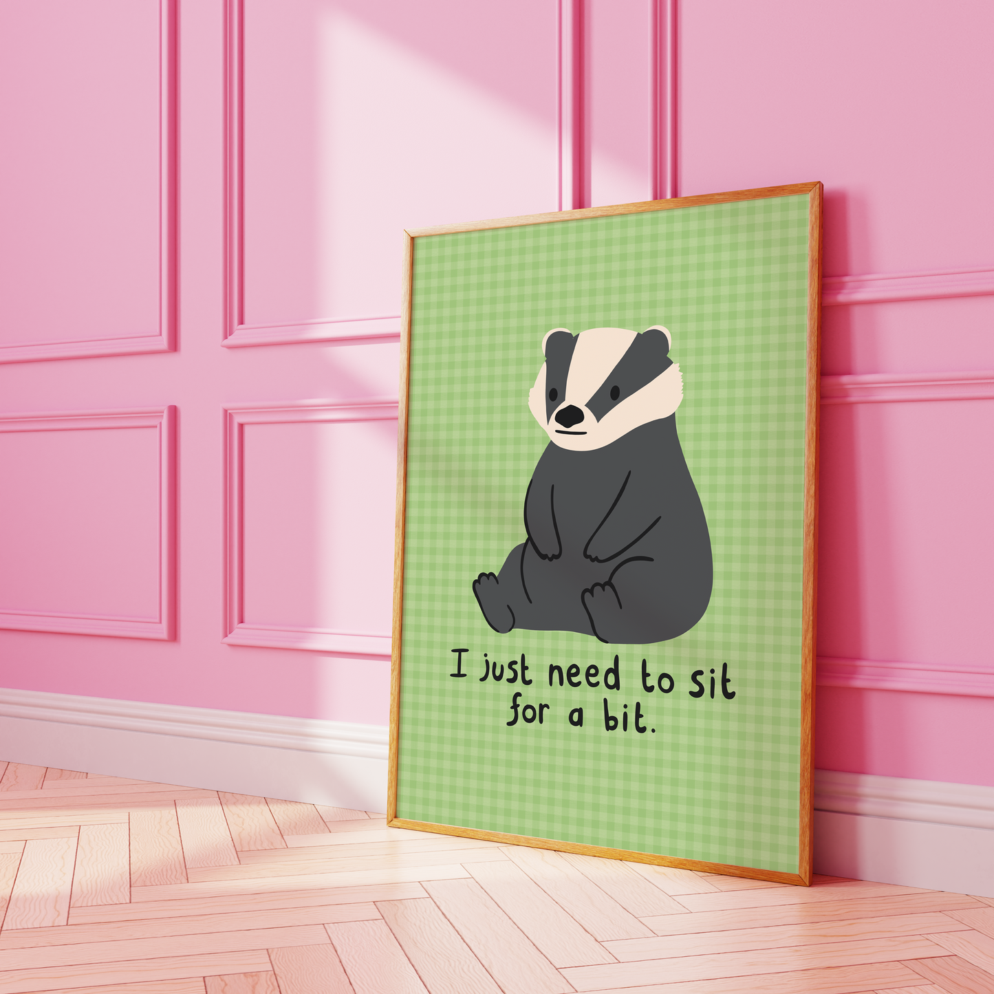A green gingham print, with an illustration of a badger sat down, and a quote that reads 'I just need to sit for a bit'.