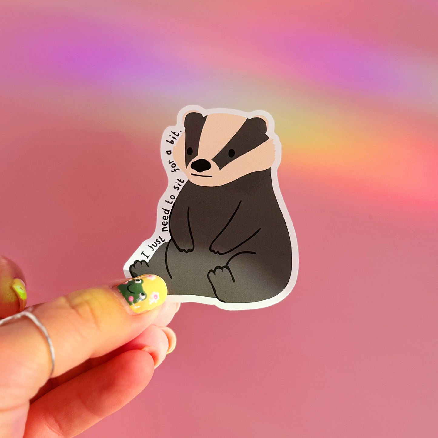 A waterproof vinyl sticker featuring a badger illustration, and text that reads 'I just need to sit for a bit'.