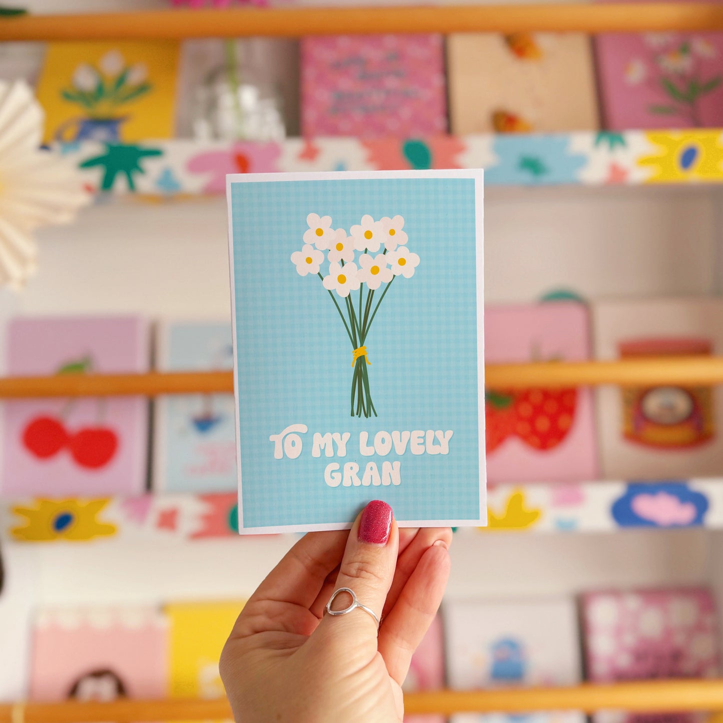 A blue greeting card with the words 'to my lovely Gran' on the front, with a bunch of daisies.