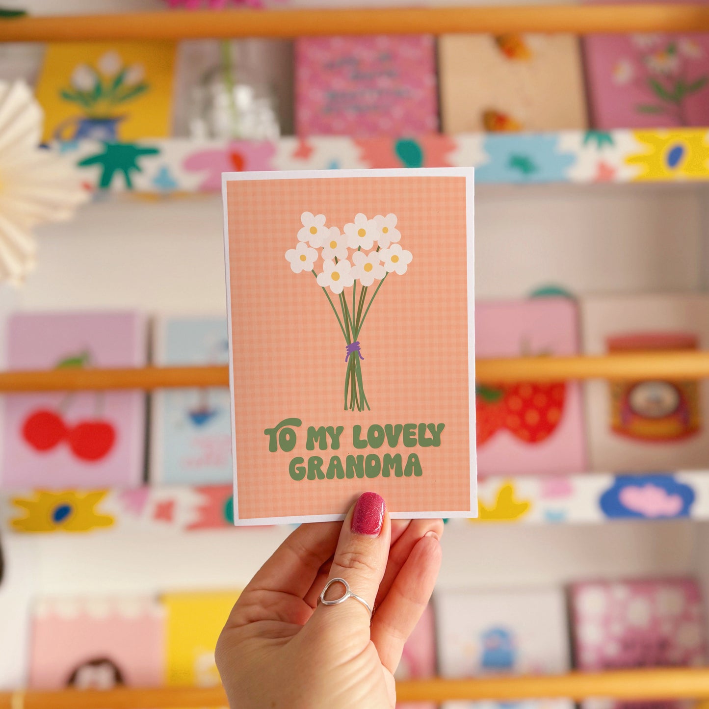 An orange greeting card with the words 'to my lovely Grandma' on the front, with a bunch of daisies.