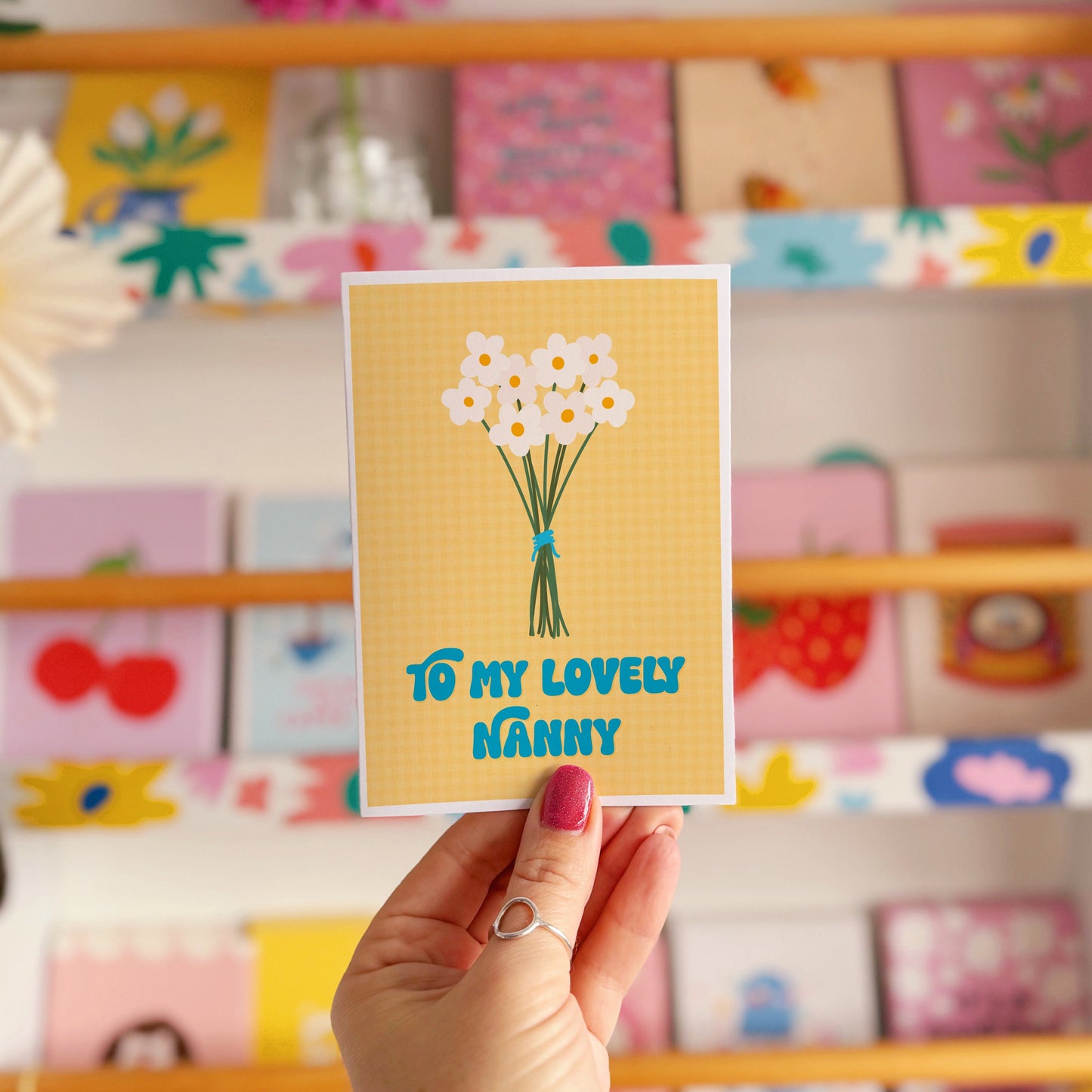 A yellow greeting card with the words 'to my lovely Nanny' on the front, with a bunch of daisies.