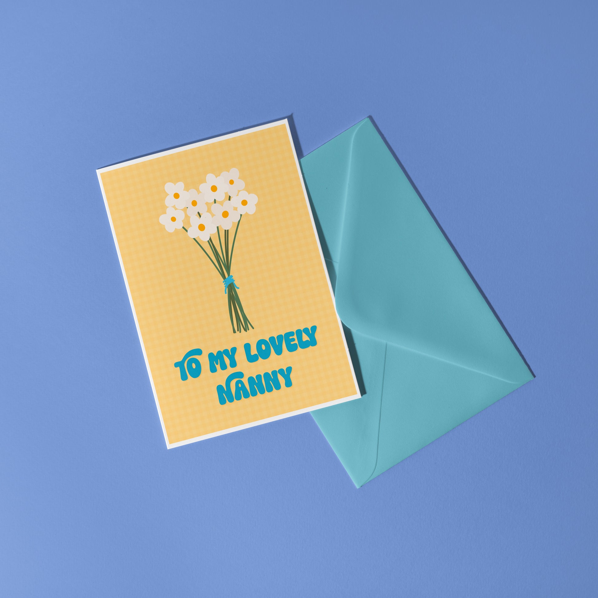 A yellow greeting card with the words 'to my lovely Nanny' on the front, with a bunch of daisies.