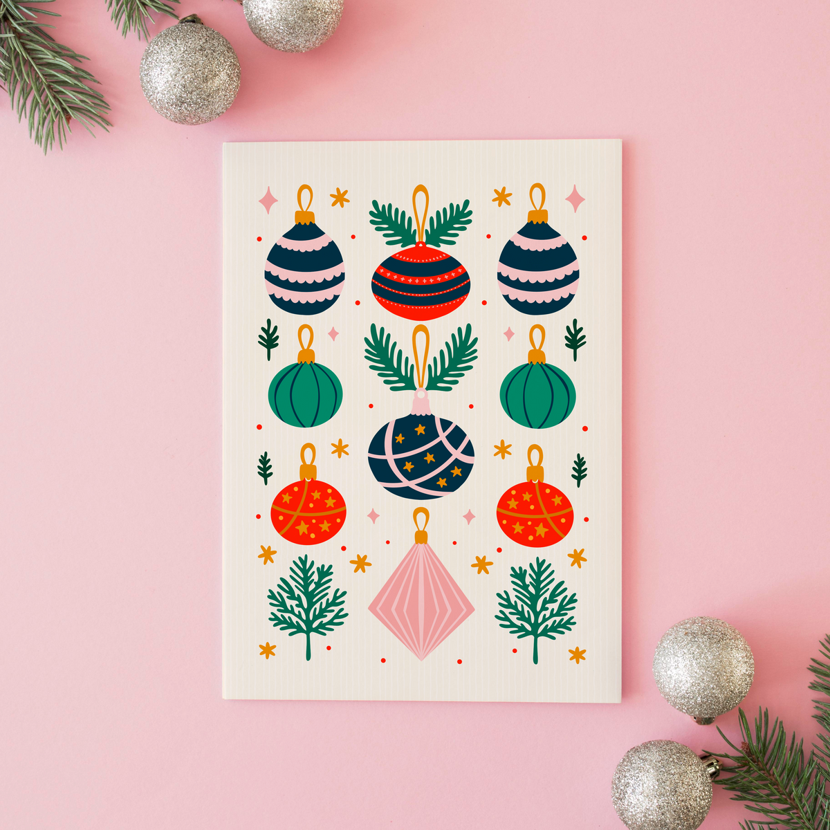 An illustrated Christmas print with 9 traditionally coloured baubles, with sprigs of pine decorating the page.