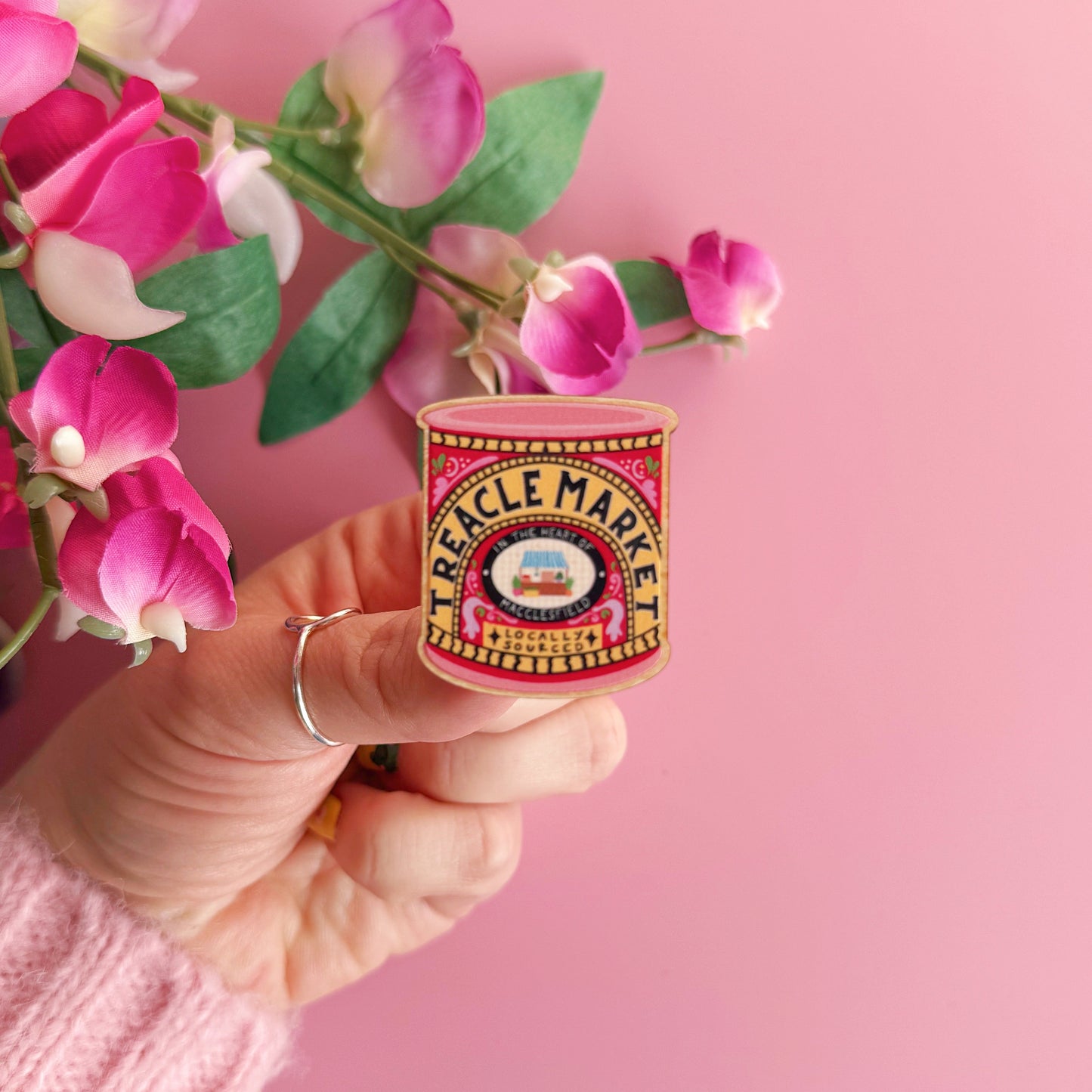 A wooden pin badge, with a glossy finish. The artwork is of a tin of treacle, but says 'treacle market' after the monthly market in Macclesfield.