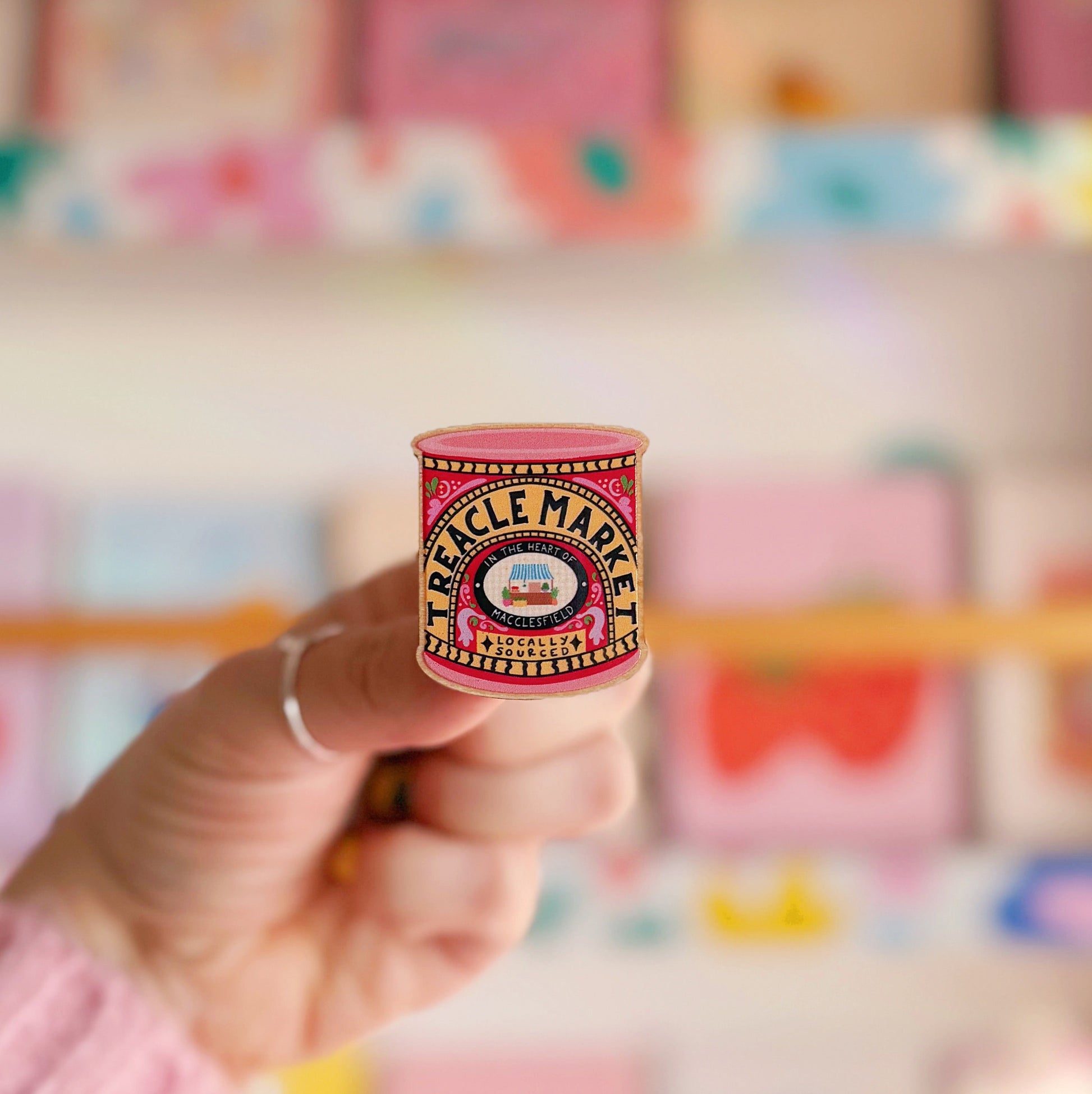 A wooden pin badge, with a glossy finish. The artwork is of a tin of treacle, but says 'treacle market' after the monthly market in Macclesfield.