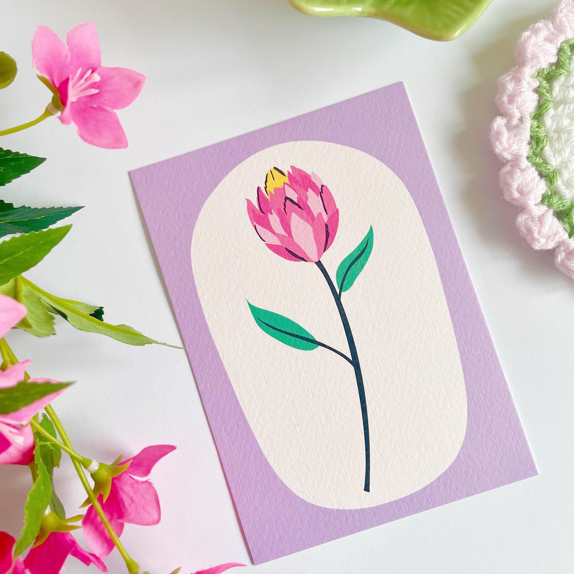 An illustration of a tulip stem, with a purple frame printed onto a textured postcard.