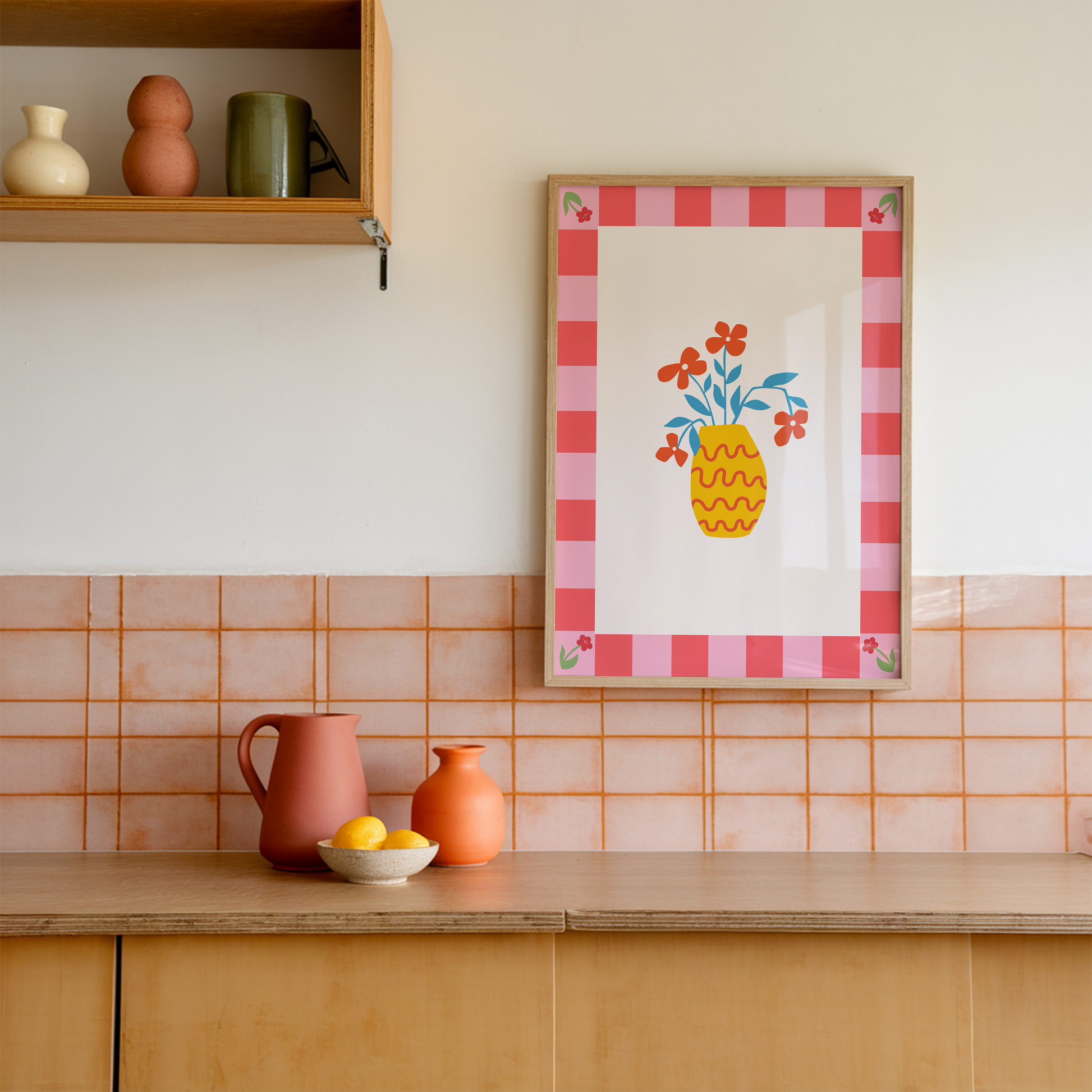 A colourful bright print, with a pink tonal checkerboard border, and an illustration of a simple modern yellow vase in the centre with red flowers.