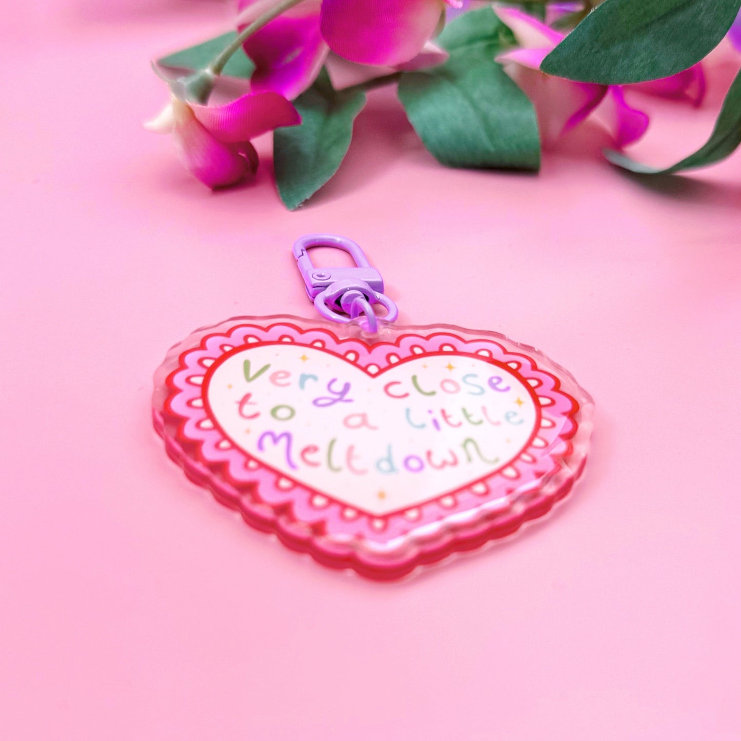 Heart-shaped keychain with text on a pink background with flowers