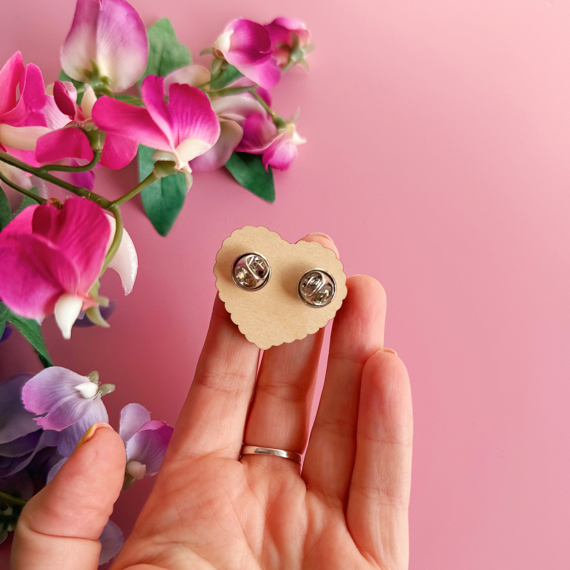 A wooden pin badge, with a glossy finish, in the shape of a heart with a funny quote in the centre.