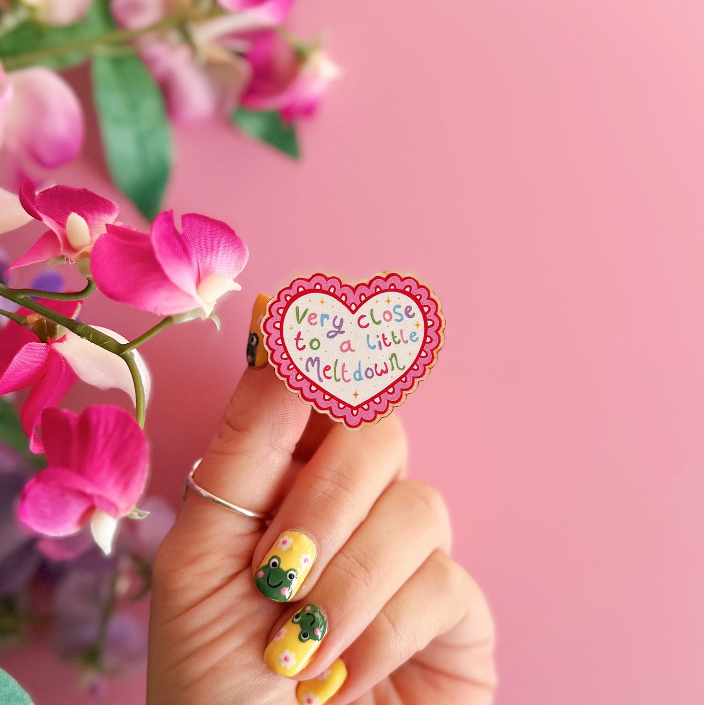 A wooden pin badge, with a glossy finish, in the shape of a heart with a funny quote in the centre.
