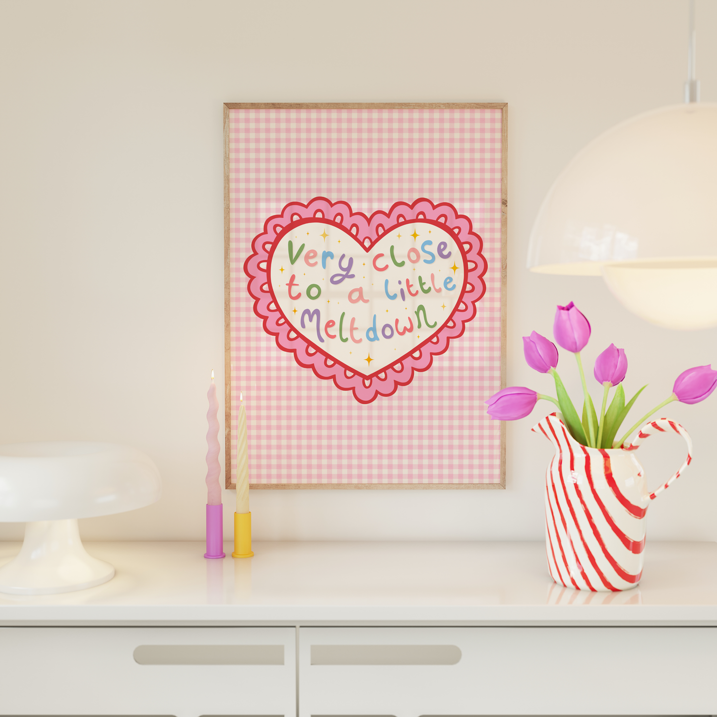 A pink print, shown in a frame, of a heart with a scallop edge. Inside the heart are the words 'very close to a little meltdown'.