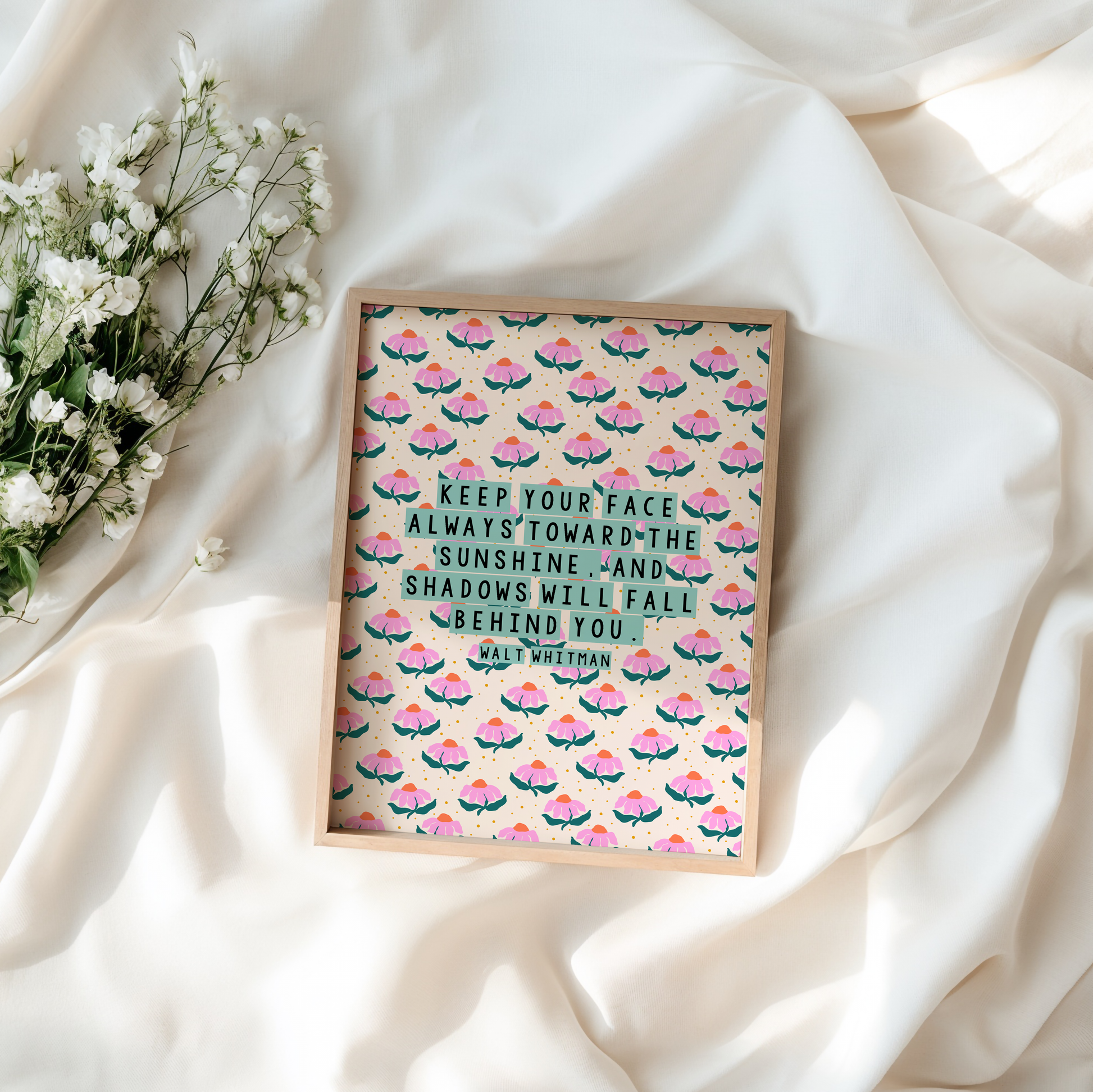 A pink, teal and cream floral patterned print, with a well known quote by Walt Whitman, saying keep our face always toward the sunshine, and the shadows will fall behind you.